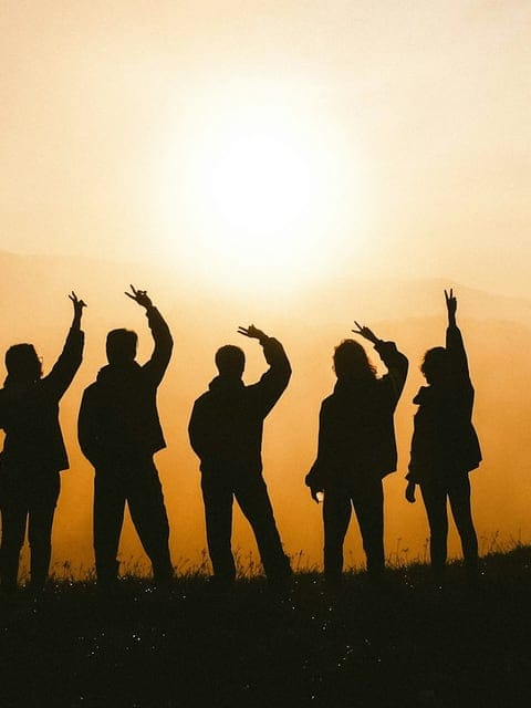 Travellers silhouetted against the sunrise, arms raised